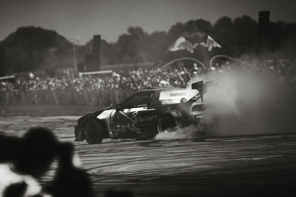 Red Bull Driftbrothers (NL) burning out tyres, covered in smoke. Spectators watching.