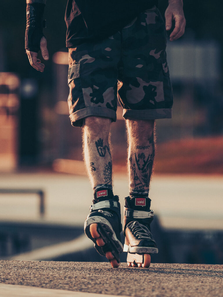 Tattooed guy on roller skates at the skate park by Ondrej Kolacek