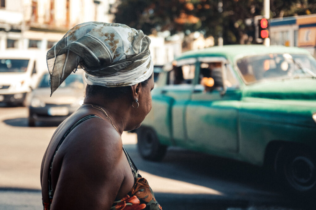 Cuban women on the street watching a classic car by ondrej kolacek
