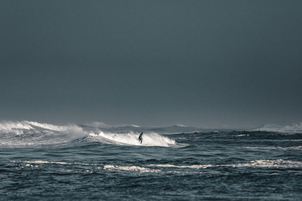 Insane waves approaching the beaches of la graviere - Hossegor, a surfer is in the water, the sky is very moody