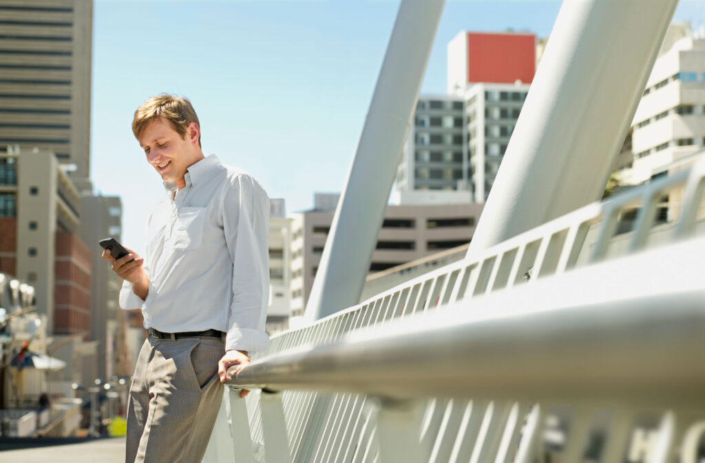 Guy on a bridge watching his mobile phone retouched