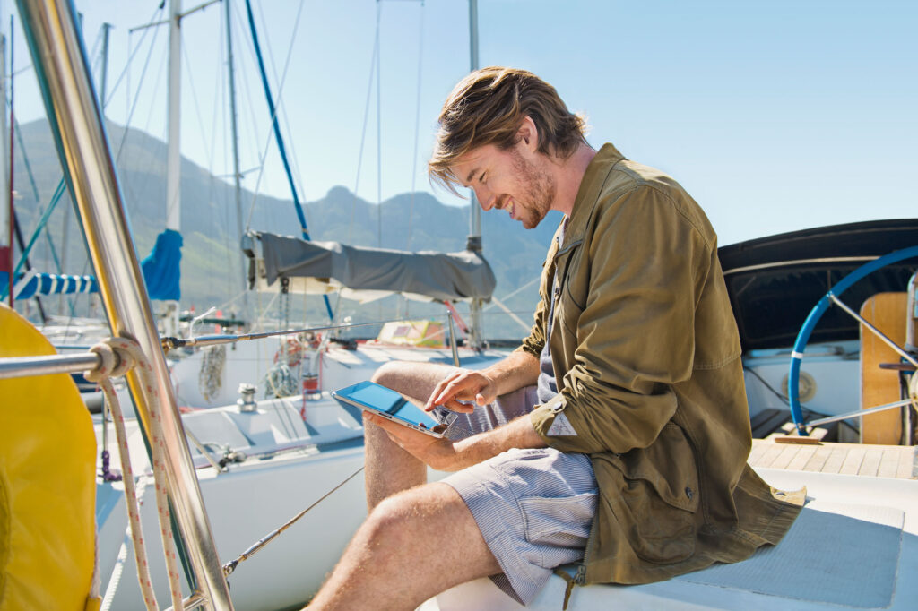 Guy on a boat is reading something on a iPad retouched