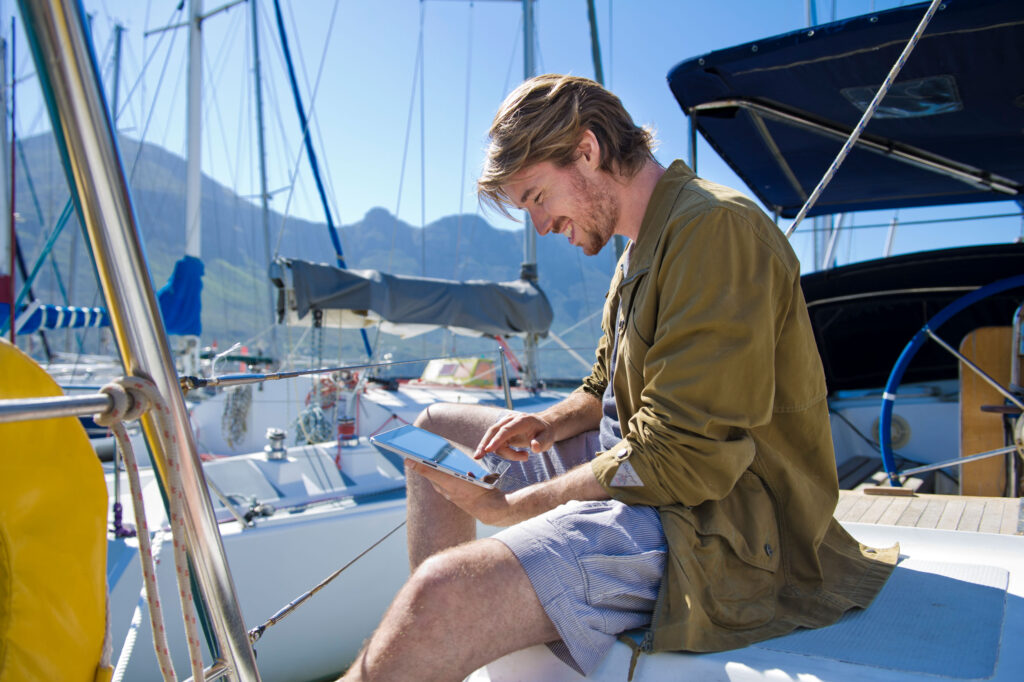 Guy on a boat is reading something on a iPad unretouched